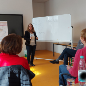 Claudia bei einer Präsentation bei einem Workshop vor mehreren Menschen als Trainerin, Entspannung & Stressabbau mit Claudia Bräuer, Heilpraktikerin & Coach
